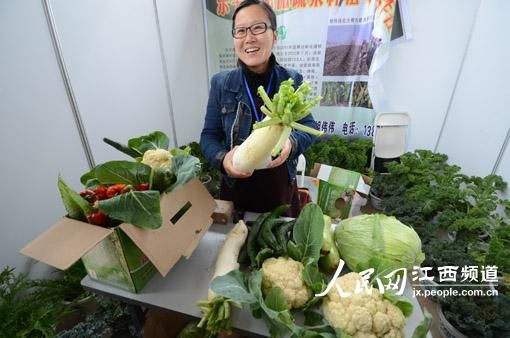 大学生村官胡伟伟向参观者介绍推介自己种的有机蔬菜（时雨 摄）